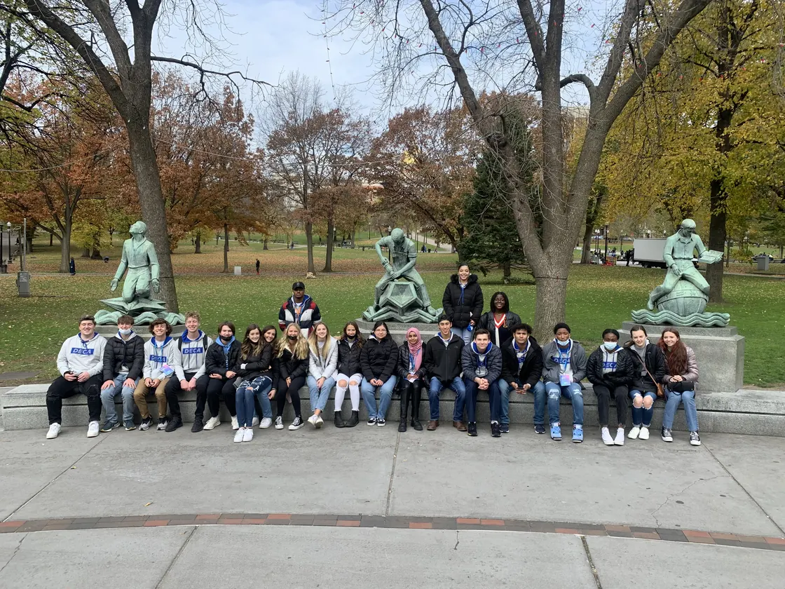 Brownsburg DECA members seated among the statues in a park on a fall trip